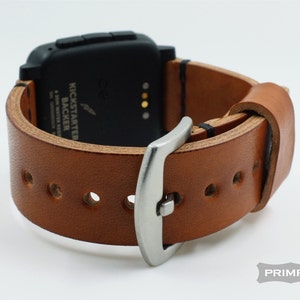 K&ouml;nnte beinhalten: Ein braunes Lederarmband mit einer silbernen Schlie&szlig;e. Das Armband ist f&uuml;r eine Smartwatch mit schwarzem Zifferblatt und vier Kn&ouml;pfen konzipiert. Der Text "Kickstarter Backer" ist auf dem Zifferblatt der Uhr sichtbar.