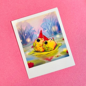 May include: Two yellow and green frogs wearing red party hats sit on a lily pad in a pond. The pond is surrounded by tall grass and the background is a soft blue and purple.