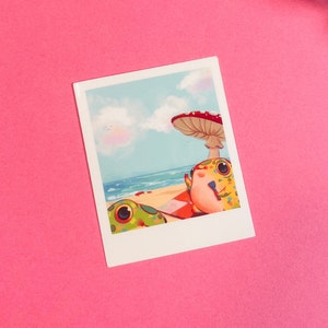 May include: A colorful illustration of two frogs relaxing on a beach under a mushroom. The frogs are green, yellow, and red with black spots. The beach is sandy with blue water and a blue sky with white clouds.