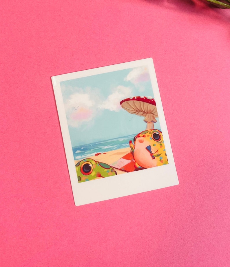 May include: A colorful illustration of two frogs relaxing on a beach under a mushroom. The frogs are green, yellow, and red with black spots. The beach is sandy with blue water and a blue sky with white clouds.