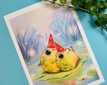 May include: Two cartoon frogs wearing party hats sit on a lily pad in a pond. The frogs are green and yellow with colorful spots. The pond is surrounded by tall grass and the background is a soft blue.