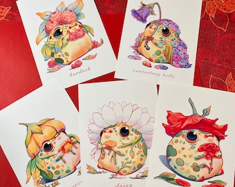 May include: Six illustrated cards featuring whimsical frog characters wearing flower crowns. Each card features a different flower, including burdock, Canterbury bells, buttercup, daisy, rose, and a sixth flower.