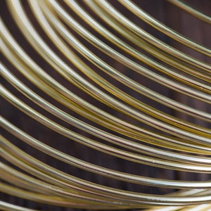 May include: Close-up of a stack of shiny gold wire, creating a circular pattern.