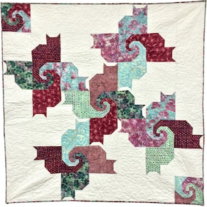 May include: A cat-themed quilt with a repeating pattern of stylized cat shapes. The cats are in burgundy, teal, and green, with floral and dotted patterns. The background is cream-colored.