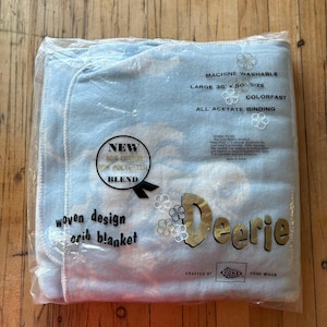 May include: A blue and white woven crib blanket with a Deerie label. The blanket is made of 60% cotton and 40% polyester and is machine washable. It is 36 inches by 50 inches and has all acetate binding. The label says "New" and "Crafted by Cone Mills".