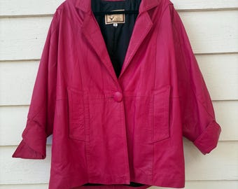 May include: A magenta leather jacket with a single-button closure and two front pockets. The jacket has a notched collar and long sleeves with folded cuffs. The interior lining is black.