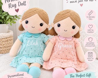 May include: Two rag dolls with brown yarn hair, embroidered facial features, and pink cheeks. One doll wears a light blue dress with white hearts and the name Lilah, the other a peach dress with white hearts and the name Gracie. Each is 15 inches tall.