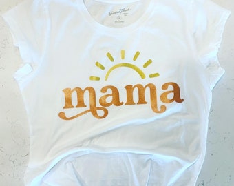 May include: White t-shirt with a gold sun and the word "mama" printed on it.