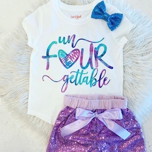 K&ouml;nnte beinhalten: Ein wei&szlig;es T-Shirt mit einer regenbogenfarbenen Grafik, auf der "fun four gettable" mit einem Herzen in der Mitte des Wortes "four" steht. Das Shirt wird mit einem lilafarbenen Pailletten-Shorts mit einer lavendelfarbenen Schleife kombiniert.
