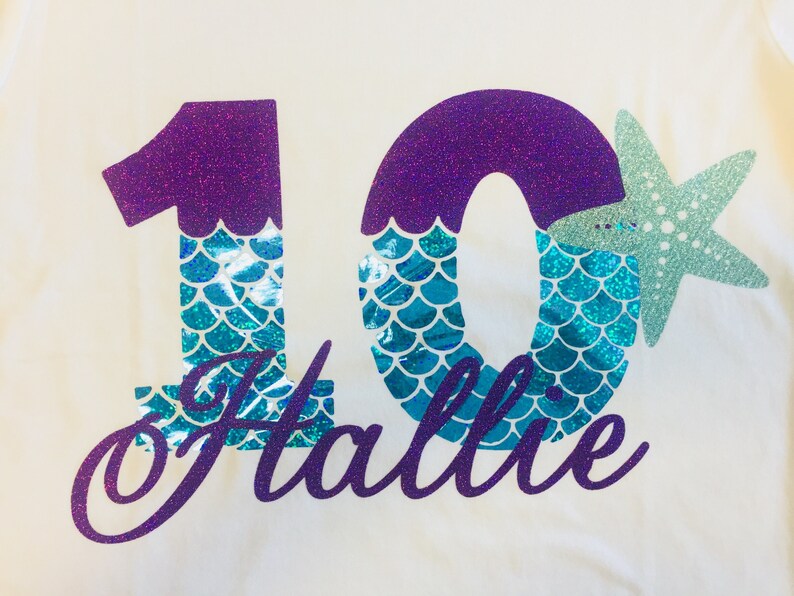 May include: Purple glitter number 10 with teal mermaid scales and a teal glitter starfish. The name "Hallie" is written in purple glitter below the number.