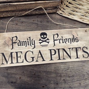 Peut inclure: Une enseigne en bois rustique avec le texte "Family & Friends MEGA PINTS" en lettres noires. Un symbole de crâne et d'os croisés est au-dessus du texte.