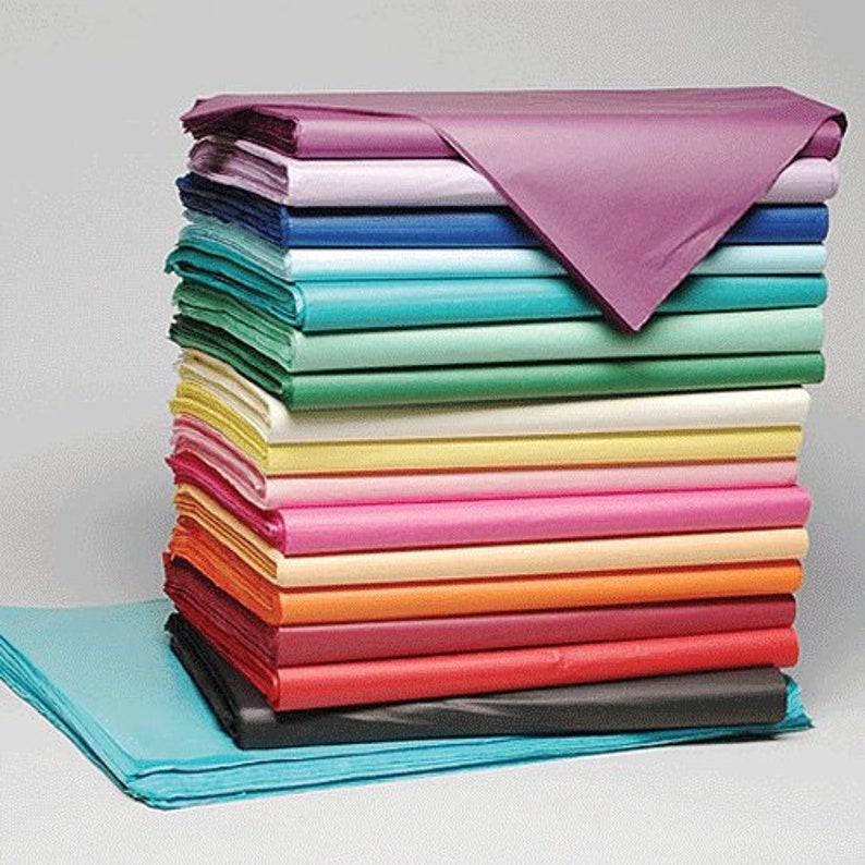 May include: A stack of colorful tissue paper in various shades of blue, green, yellow, pink, orange, red, and black. The tissue paper is folded neatly and stacked on top of each other.