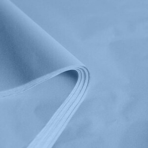 May include: A stack of light blue tissue paper. The paper is folded in half and the edges are visible.