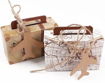 May include: Two brown paper gift boxes shaped like suitcases with a world map design and a brown paper airplane tag attached to each. The boxes are tied with twine.
