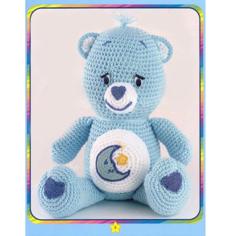 May include: A crocheted blue teddy bear with a white belly and a crescent moon and star design. The bear has a blue nose and blue eyes.