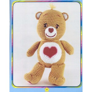 May include: A crocheted Care Bear plush toy with a brown body, white belly, and a red heart on its chest. The bear has a pink nose and a yellow bow on its head.
