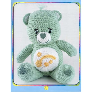 May include: A crocheted green teddy bear with a white belly featuring a yellow rainbow and stars. The bear has a heart-shaped nose and black eyes.