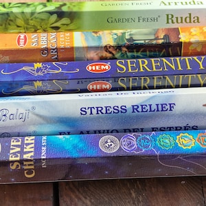Può includere: Una collezione di scatole di bastoncini di incenso, con marchi come HEM e Balaji. Le scatole mostrano testi come "Serenity", "Stress Relief" e "Seven Chakra". I colori delle confezioni includono verde, arancione, blu e viola.