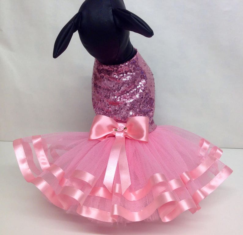 May include: Pink sequined dog dress with a tulle skirt and pink satin ribbon bow.