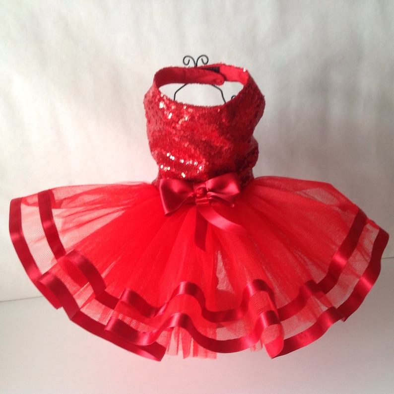 May include: Red sequined bodice tutu dress with a red satin bow and red satin ribbon trim.