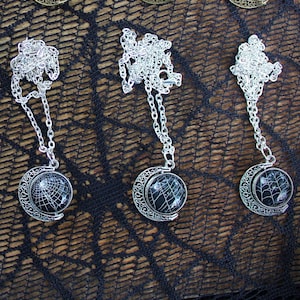 May include: Ten silver and bronze necklaces with black and white globe pendants. The globes have a spiderweb design.