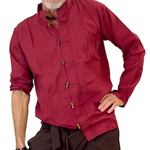 Può includere: Una camicia a maniche lunghe color granata con bottoni in legno e un paio di pantaloni cargo marroni con una cintura nera.