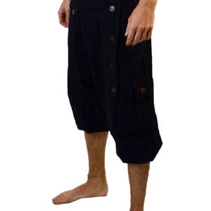 May include: Black cargo shorts with a unique button-up design and a large cargo pocket on the right leg.