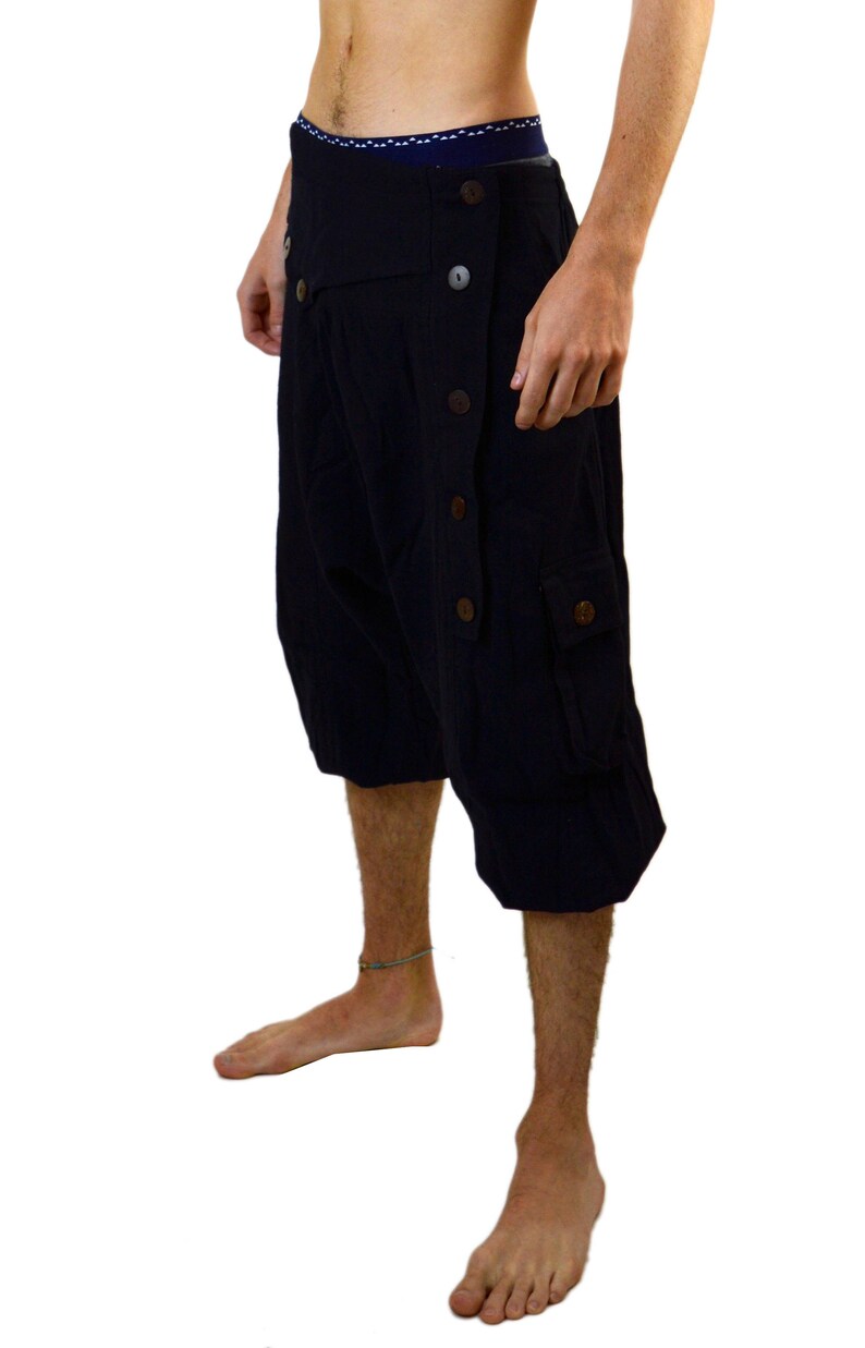May include: Black cargo shorts with a unique button-up design and a large cargo pocket on the right leg.