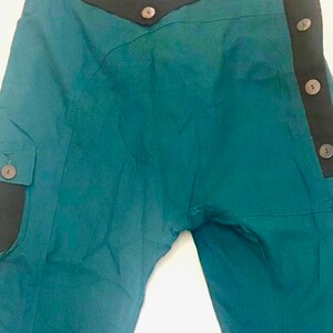 May include: Teal blue trousers with a black waistband and multiple brown buttons down the side.