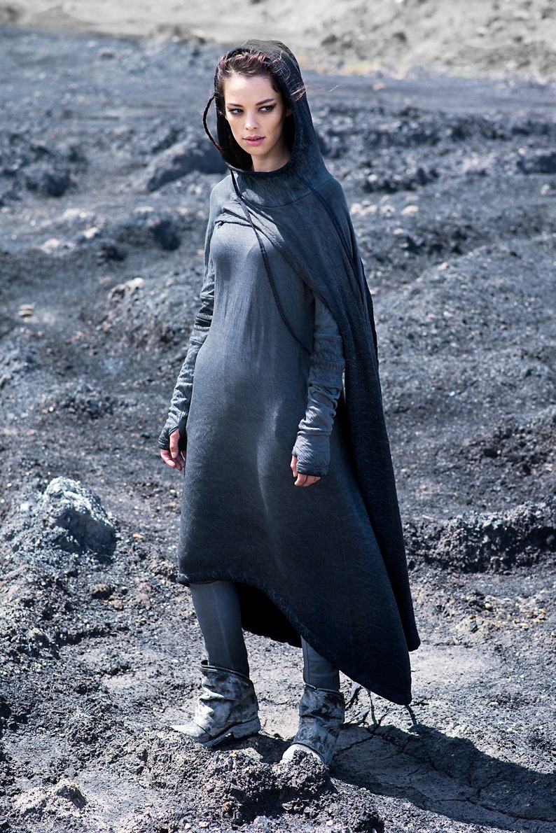 Puede incluir: Un vestido con capucha gris oscuro con una capa fluida, mangas largas y leggings a juego. El atuendo se completa con botas texturizadas. Este conjunto monocrom&aacute;tico es adecuado para cosplay o eventos de fantas&iacute;a.