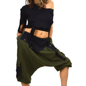 May include: A woman wearing a black top and green and black harem pants with buttons. She is wearing a gold headpiece with blue stones.