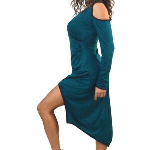 May include: A teal-colored dress with long sleeves and an asymmetrical hemline. The dress features a cold-shoulder design and a ruched detail on the side. The model is wearing burgundy high-top sneakers.