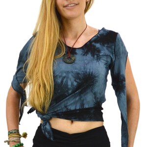 May include: A tie-dye top in shades of blue and black, knotted at the waist, with long sleeves that are tied at the elbow. The model is also wearing black pants and a necklace with a circular pendant.