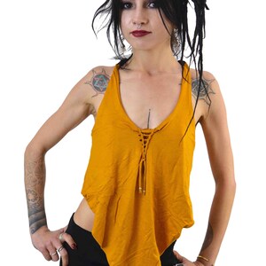 May include: A mustard yellow sleeveless top with a lace-up detail at the neckline. The top is asymmetrical and has a flowing, relaxed fit.