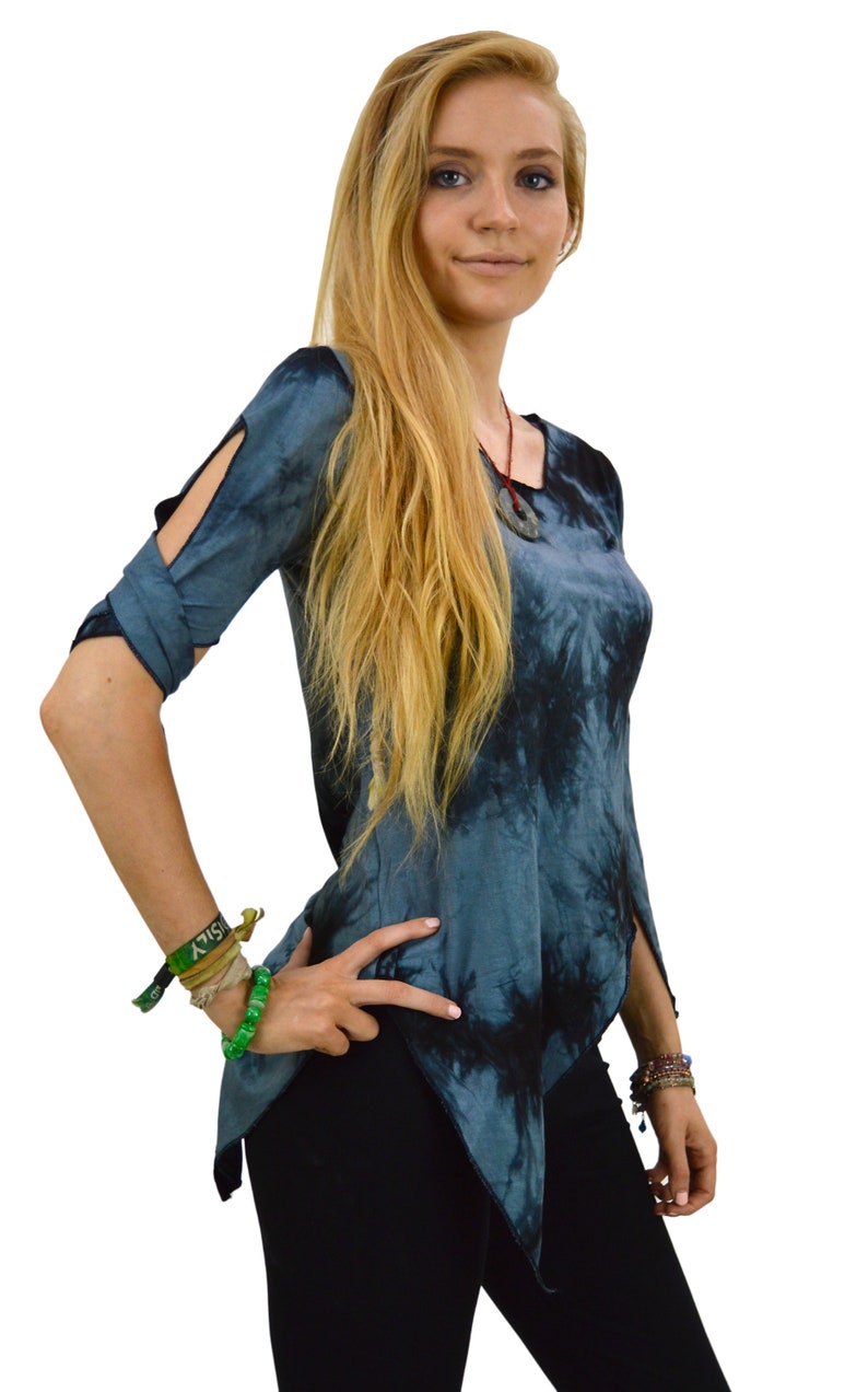 May include: A blue and black tie-dye top with a unique asymmetrical hemline and sleeve cutouts. The top is paired with black pants. The model is wearing bracelets and a necklace.