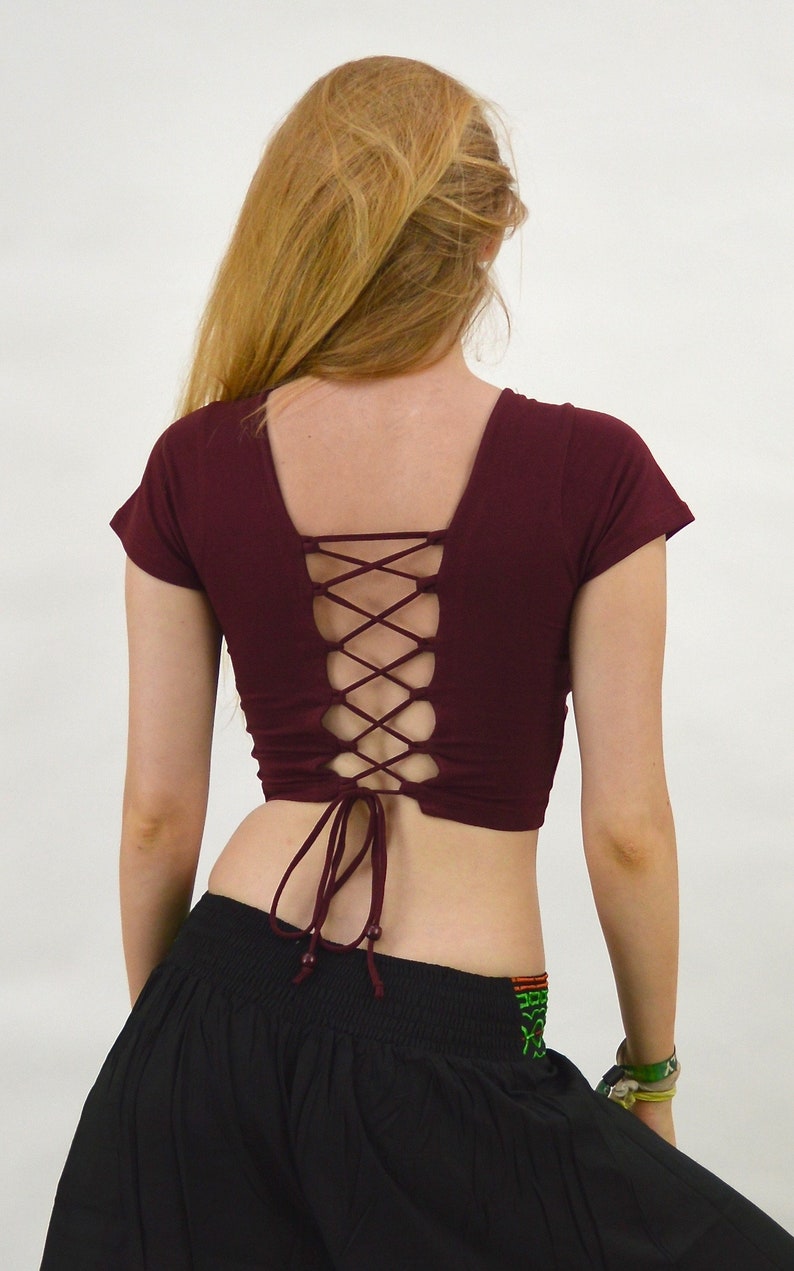 May include: A maroon crop top with short sleeves and a lace-up back. The top is tied at the waist.