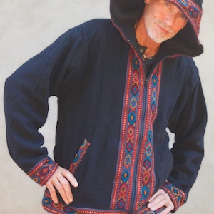 Può includere: Una giacca nera con cappuccio, chiusura a zip e bordi con motivo geometrico colorato. La giacca ha una vestibilità rilassata e uno stile casual.