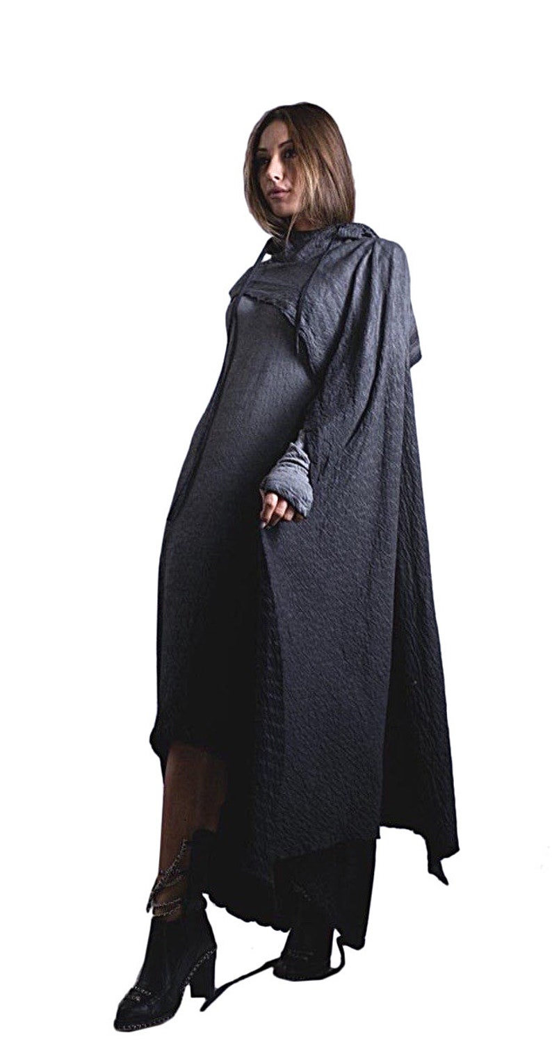 Puede incluir: Un vestido fluido gris oscuro con una capa a juego. El vestido tiene mangas largas y una tela texturizada. La modelo lleva botines negros con detalles de cadena. El fondo es blanco liso.