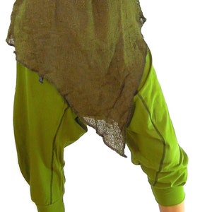 May include: An outfit featuring olive green, loose-fitting pants and a matching top with a frayed hem. The ensemble includes rust-colored, laced-up sandals. The clothing appears to be made of natural fabrics.