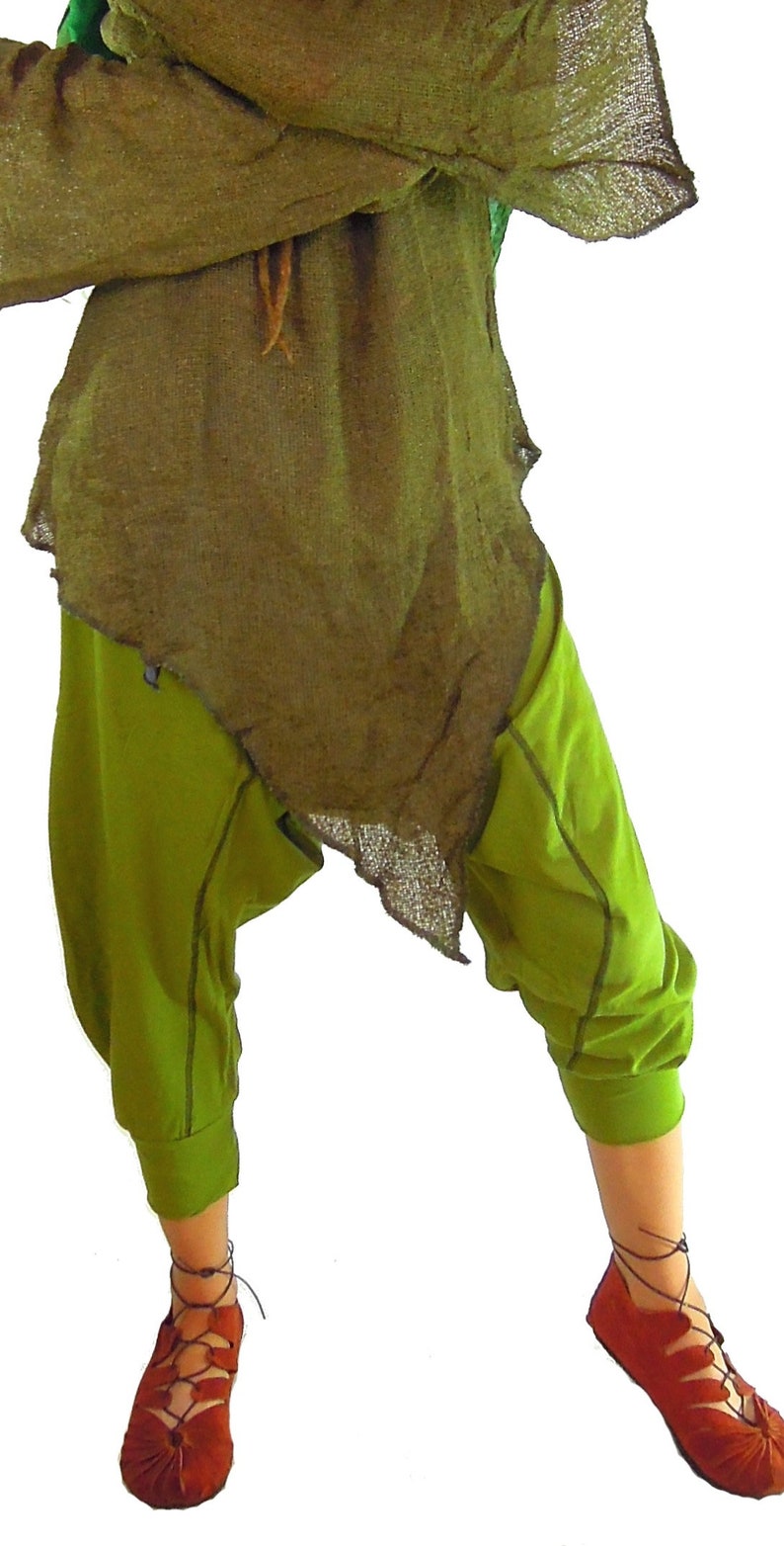 May include: An outfit featuring olive green, loose-fitting pants and a matching top with a frayed hem. The ensemble includes rust-colored, laced-up sandals. The clothing appears to be made of natural fabrics.
