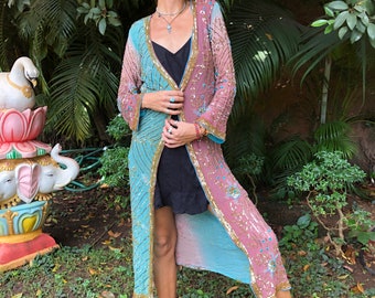 May include: A long, sequined, blue and pink robe with gold accents. The robe is open in the front and has a black undershirt. The person is wearing sandals.