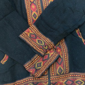 Puede incluir: Chaqueta negra con cierre de cremallera y ribetes de colores con patrones geom&eacute;tricos.