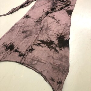 May include: A mauve and black tie-dye skirt. The skirt features an asymmetrical cut and a long tie. The fabric is lightweight and has a crinkled texture. The skirt's length is approximately 100 cm.