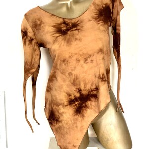 May include: A tie-dye long-sleeve shirt in shades of brown and tan. The shirt has an asymmetrical hemline and long, flowing sleeves with tie details. The neckline and edges are finished with a brown stitch.