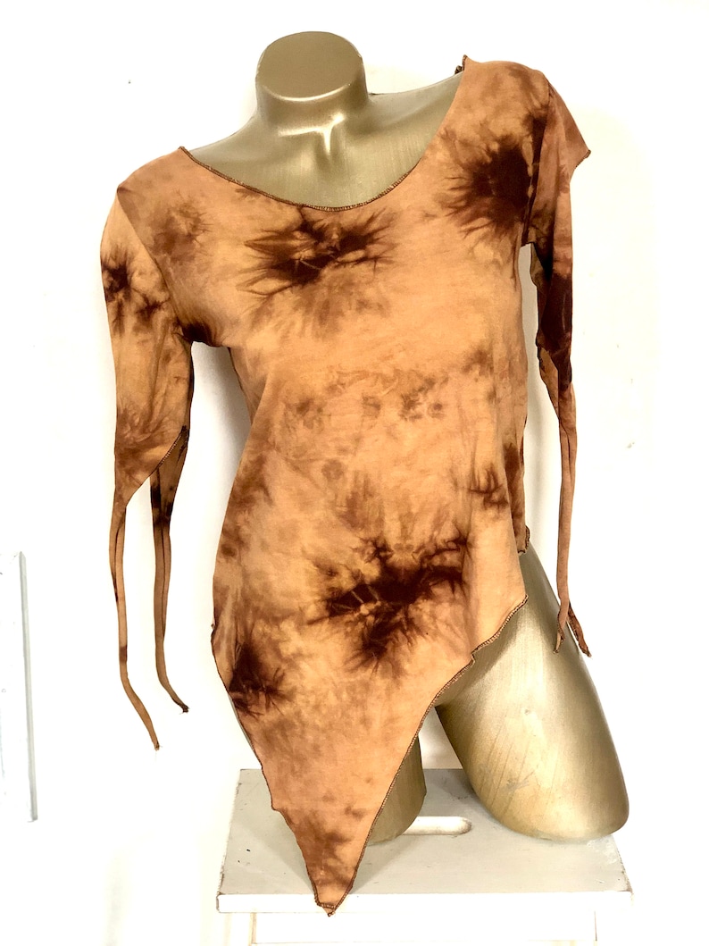 May include: A tie-dye long-sleeve shirt in shades of brown and tan. The shirt has an asymmetrical hemline and long, flowing sleeves with tie details. The neckline and edges are finished with a brown stitch.