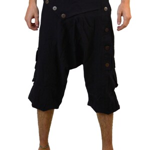 May include: Black cotton shorts with a unique design featuring a wrap-around front and multiple button closures. The shorts have a loose, comfortable fit and are perfect for a casual, bohemian style.