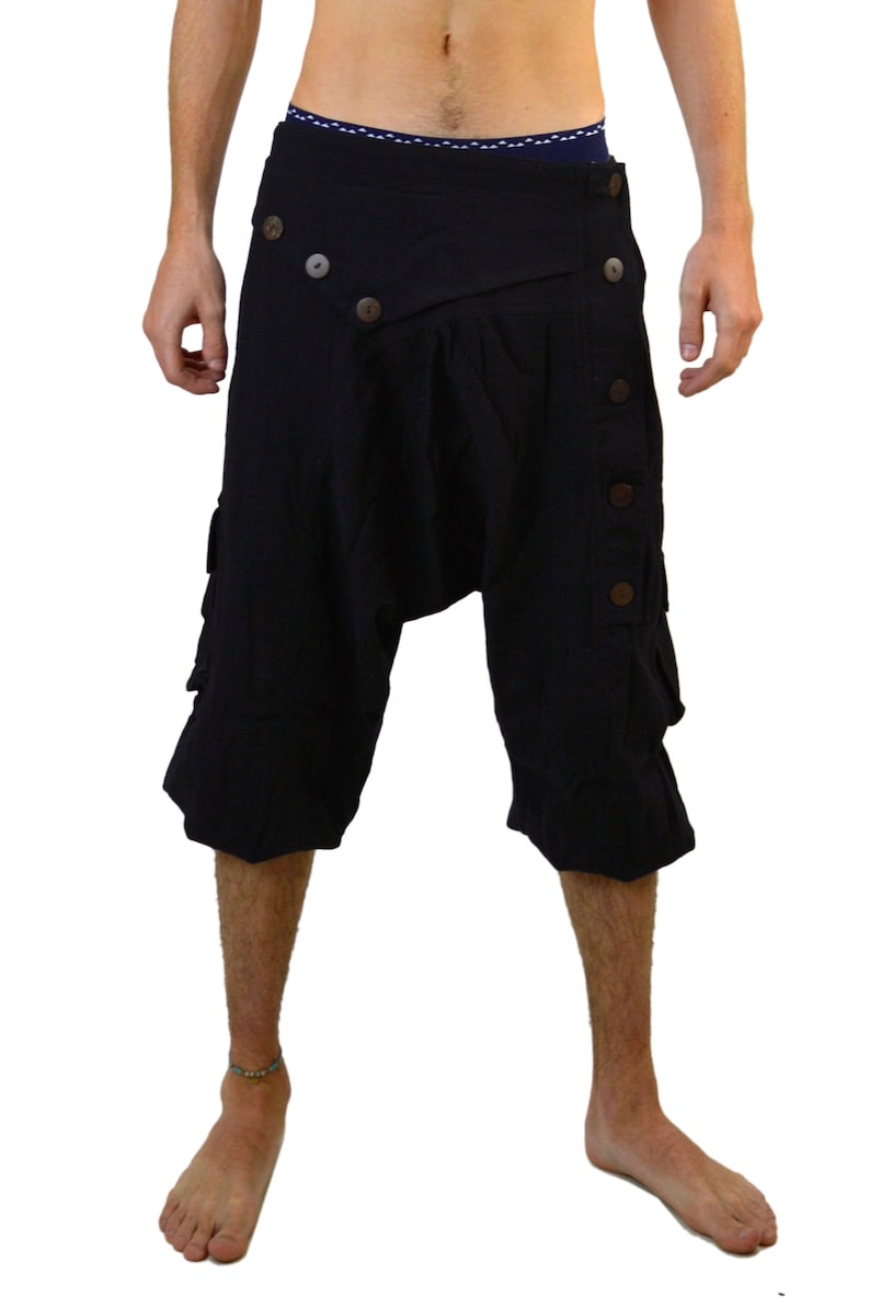 May include: Black cotton shorts with a unique design featuring a wrap-around front and multiple button closures. The shorts have a loose, comfortable fit and are perfect for a casual, bohemian style.