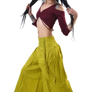 May include: A burgundy long-sleeve crop top with cut-out shoulders and olive green wide-leg pants. The outfit is made of soft fabric. The model is wearing black shoes.