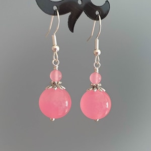 May include: A pair of dangle earrings with pink round beads and silver accents.