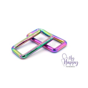 May include: Two iridescent rainbow-colored metal D-rings, stacked on top of each other. The rings are rectangular in shape with rounded corners.